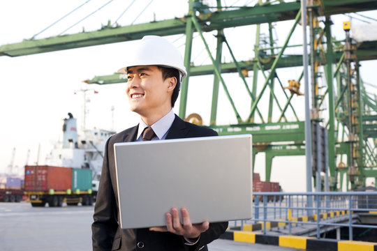 businessman using a laptop at a shipping port