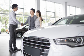 Fototapeta na wymiar Young couple buying car in showroom