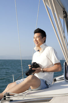 Happy man holding a camera on the boat deck