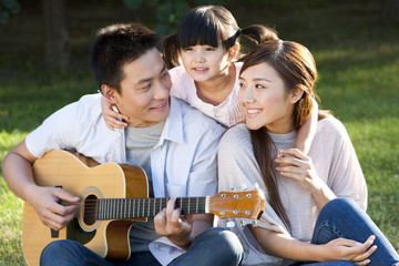 Young family in a park with a guitar