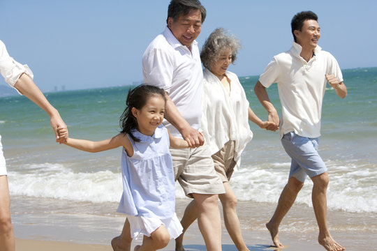 A happy family holding hands and running on beach