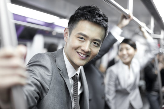 Cheerful Chinese businessman with partners in subway train
