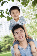 Little boy sitting on his father's shoulders