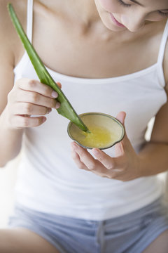 Young woman extracting aloe vera gel in a bowl