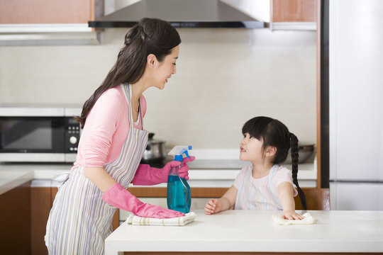 Mother And Daughter Cleaning Kitchen Counter