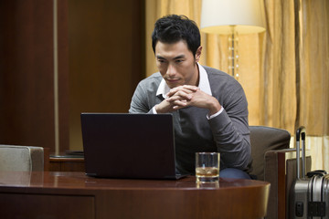 Fototapeta na wymiar Young businessman using laptop in hotel room