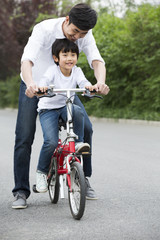 Obraz premium Father teaching son to ride a bicycle