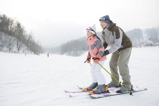 Young father teaching daughter to ski