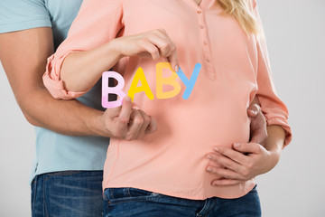 Expecting Couple Holding Word Baby