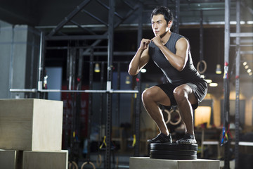 Obraz na płótnie Canvas Young man doing box jump in crossfit gym