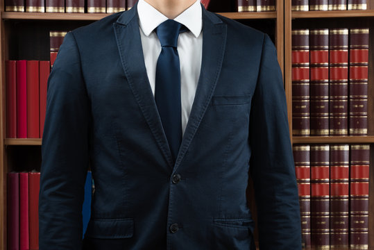 Midsection Of Lawyer Standing Against Bookshelf