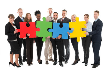 Fototapeta premium Portrait Of Happy Business Team Holding Jigsaw Pieces
