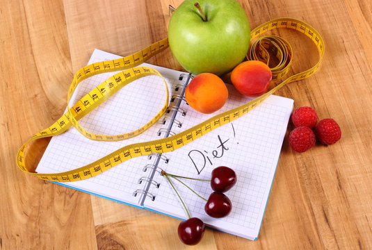 Fruits and centimeter with notebook, slimming and healthy food