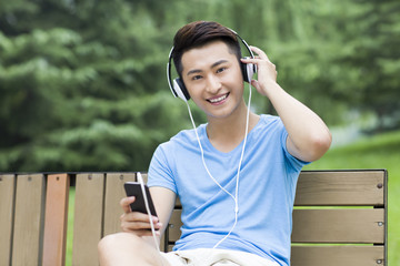 Young man enjoying music in park