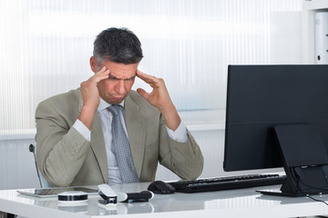 Mature Businessman Suffering From Headache At Desk