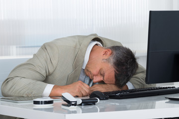 Tired Mature Businessman Sleeping On Desk