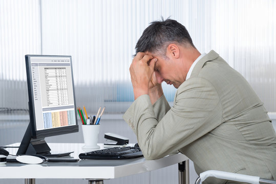 Accountant Suffering From Headache At Desk