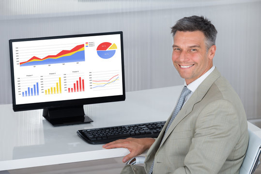Happy Businessman Analyzing Financial Graphs On Computer