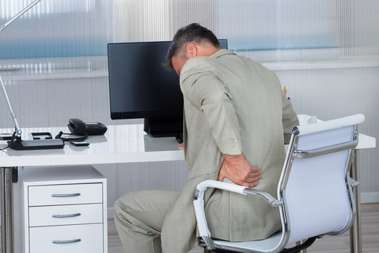 Businessman Suffering From Backache On Chair