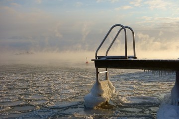 Ice covered swimming jetty and buoy in the freezing Baltic Sea in Helsinki, Finland just hours before complete freeze over of the sea on an extremely cold January morning (-20C) on 6 January 2016. 
