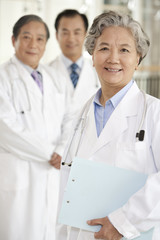 Fototapeta premium Senior Female Doctor with Two Doctors in Background