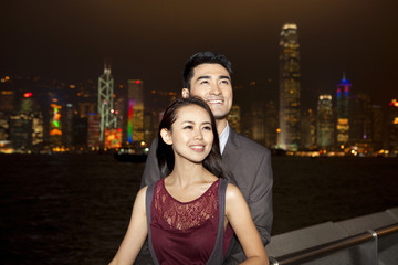 Happy young couple enjoying the night view of Victoria Harbor, Hong Kong