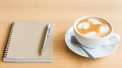 Coffee cup and notebook on grunge wooden background