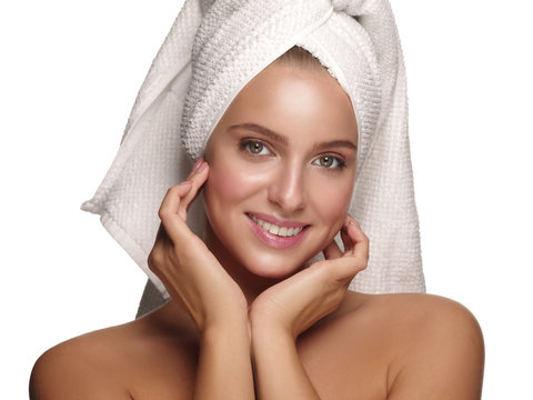 Portrait of a young healthy and beautiful girl with a towel on her head doing daily skincare after shower