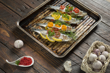 Cooking fresh herring fish with garlic lemon dill cherry tomatoes