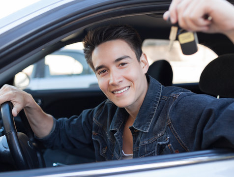 Handsome male driver showing car key.