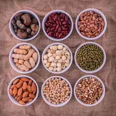 Mixed beans , lentils and nuts in the white bowl on brown cloth
