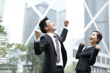 Excited business colleagues punching the air outdoors, Hong Kong