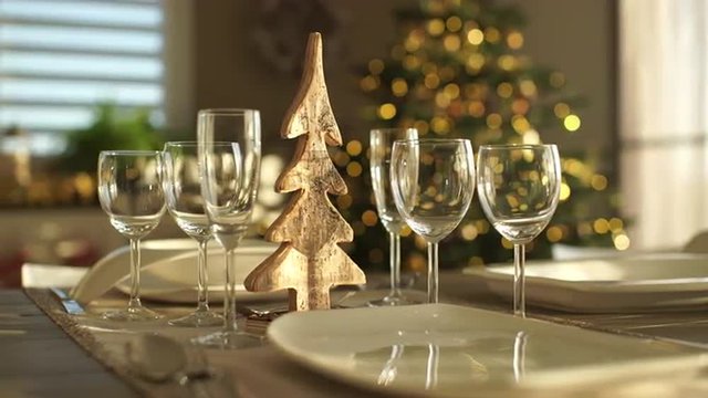 4k footage, dolly move closeup glasses and plates on decorated dining table in living room of town house with christmas tree, captured with atomos shogun
