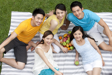 young people having picnic on meadow