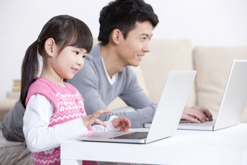Little girl and father surfing the net with laptop
