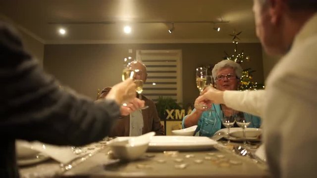 4k footage, four happy seniors sitting on dining table at home on christmas eve cheering with champagne, captured with atomos shogun
