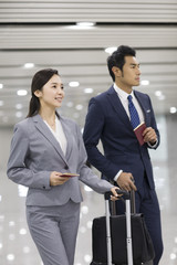 Young business person walking in airport with suitcases