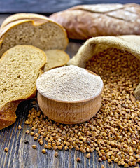 Flour buckwheat in bowl with cereals and breads on board
