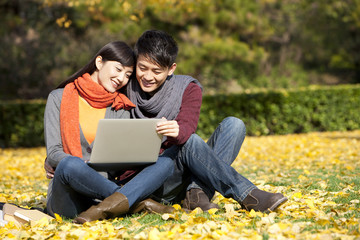Sweet young couple sharing laptop in a beautiful autumn day