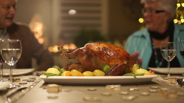 4k footage, dolly move seniors sitting on dining table on christmas eve at home with roasted turkey for dinner, captured with atomos shogun
