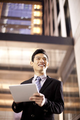 Fototapeta premium A businessman using a digital tablet outside an office building at night