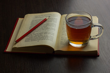 Cup of tea on table with book and pencil