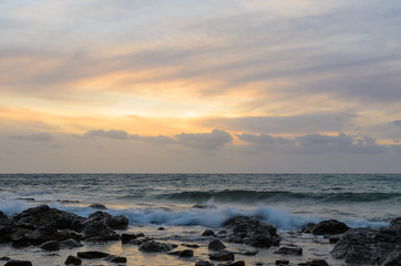 Obraz premium Dramatic sunset at the ocean with boulder rocks