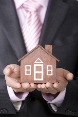 Businessman holding a small wooden model home