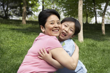 Portrait Of A Grandmother And Grandson Hugging In The Park