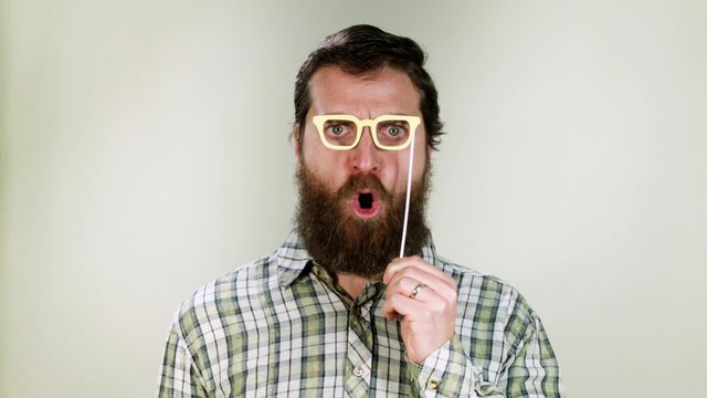 Funny hipster man playing with toy glasses. It's carnival