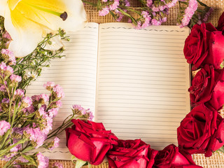rose and empty notebook page on wood background