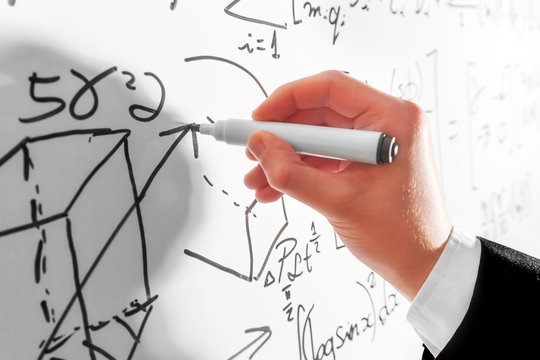 Man writing complex math formulas on whiteboard. Mathematics and science