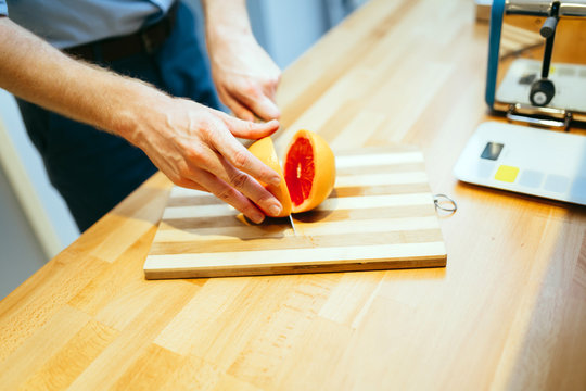 Man slicing orange in kitchen