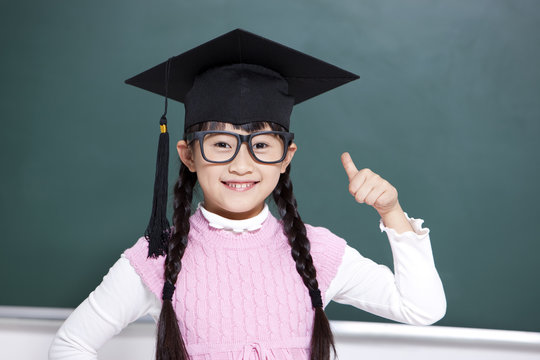 Lovely schoolgirl with a mortar board doing thumbs up